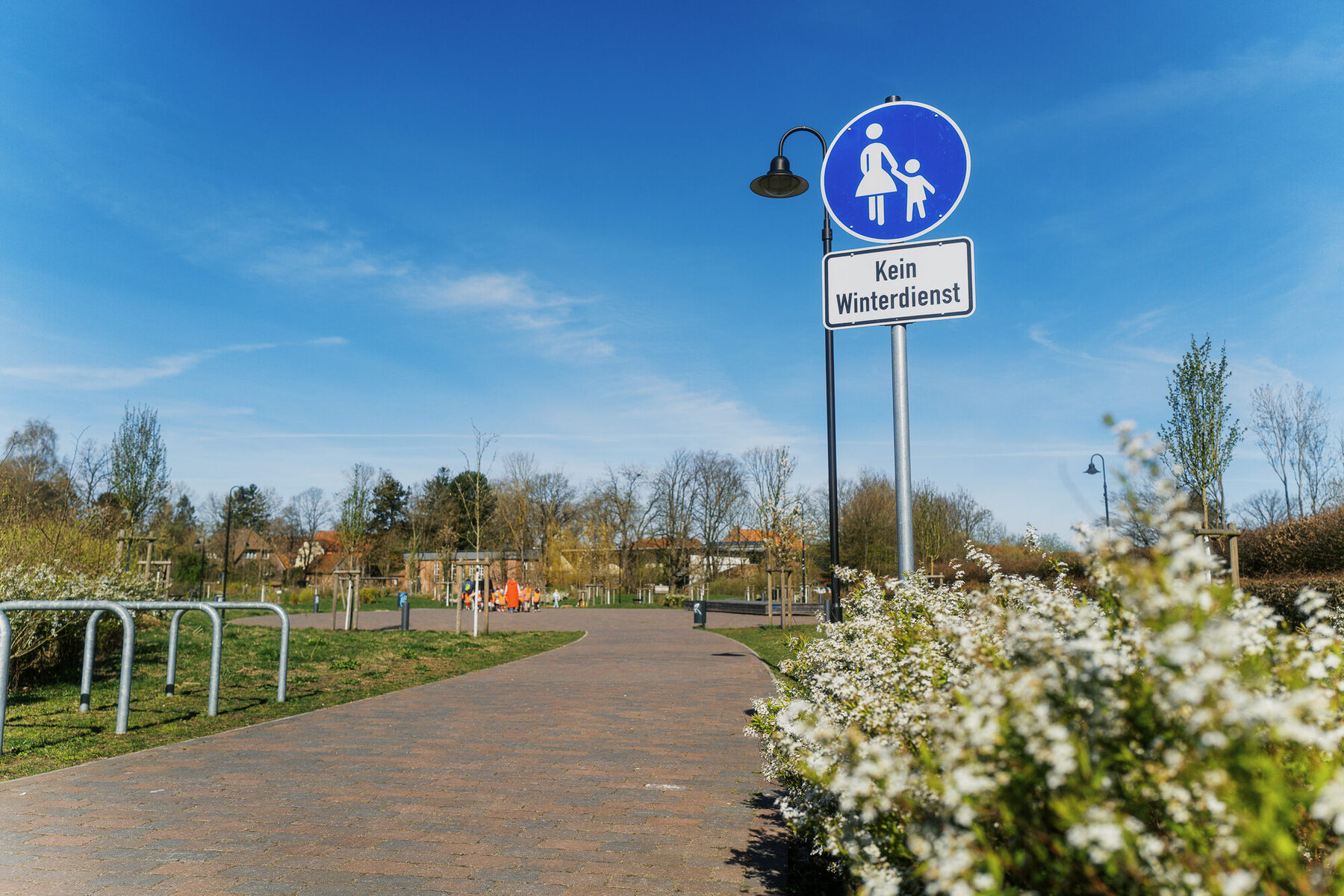 Fahrradwegschild an einem ruhigen Weg mit blühendem Strauch
